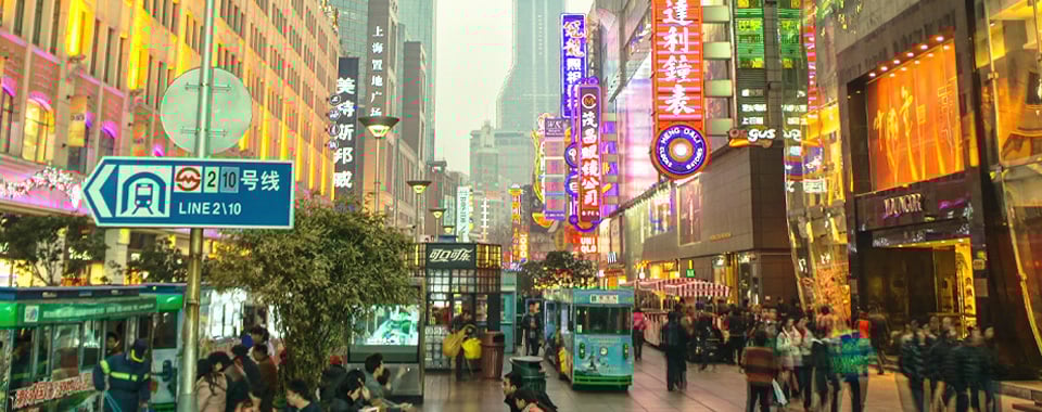 People walking along the street in Shanghai with billboards around