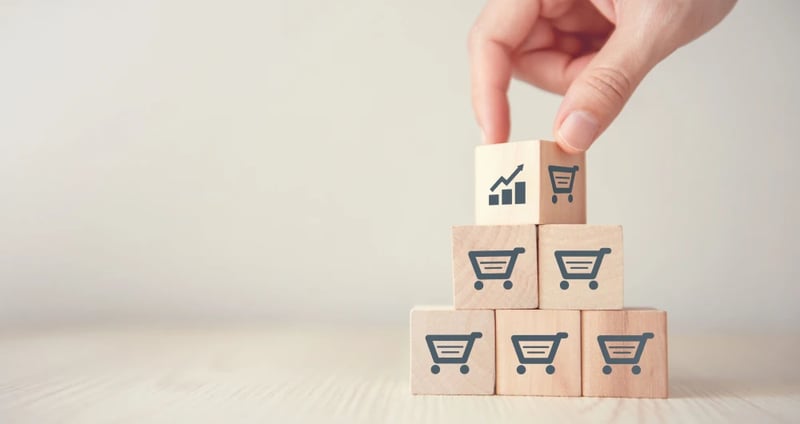 Small wooden blocks stacked on top of each other, with shopping carts on each of the blocks